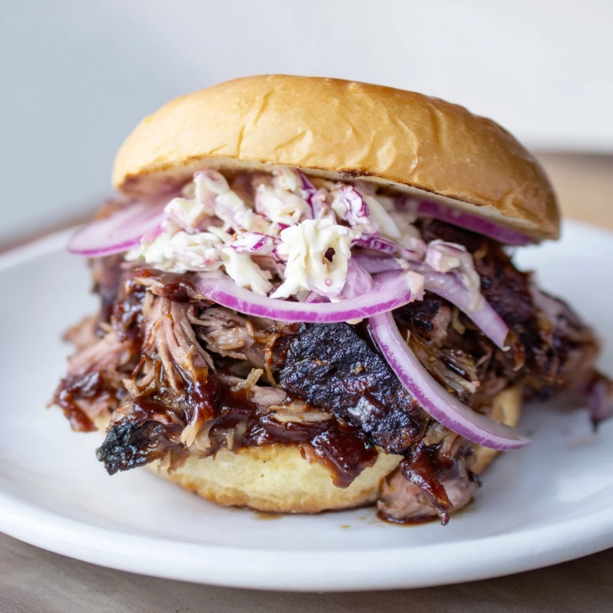 Close-up of a Fire-Kissed BBQ Pulled Pork Sandwich, showing tender meat, glistening sauce, and fresh herbs.