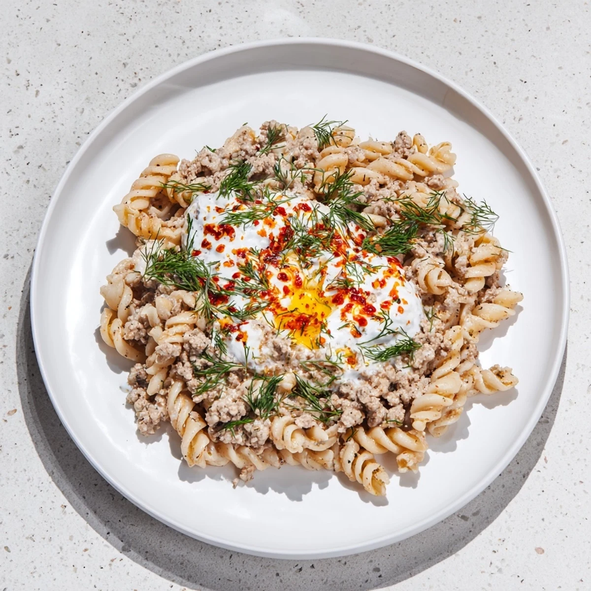 Flavorful Turkish Pasta with Ground Turkey: a delicious meal topped with fresh herbs and a buttery drizzle.