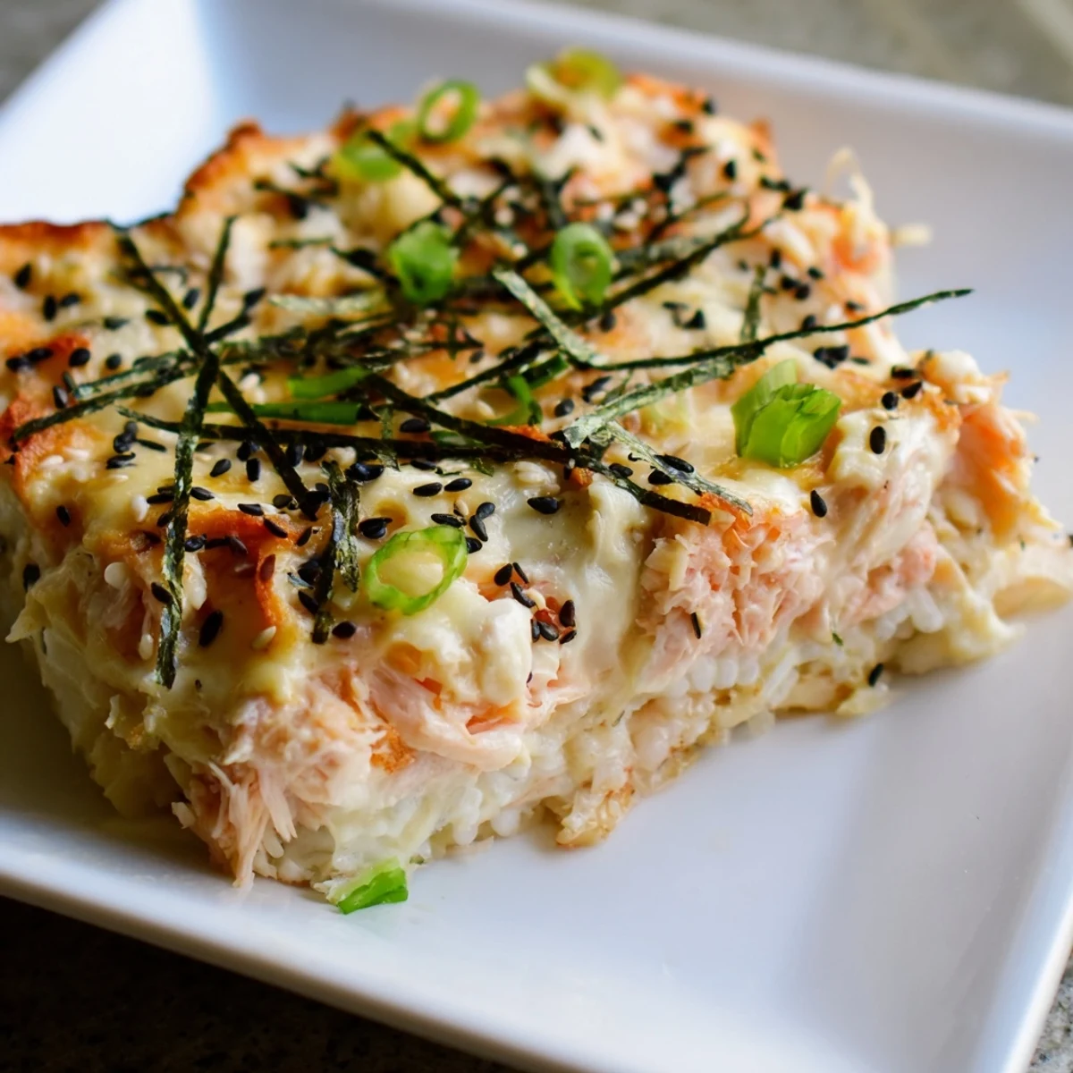 Delectable Creamy Salmon Sushi Bake, a baked casserole bubbling with melted cheese and flaky salmon.