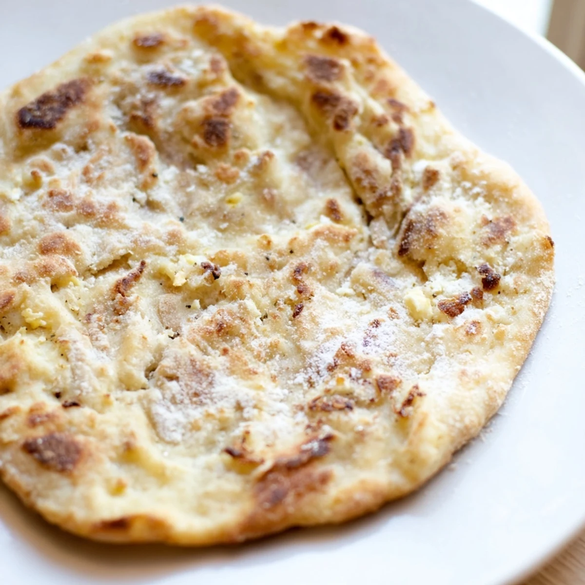 Golden cottage cheese flatbread, pan-fried and ready to eat, with a blistered surface.