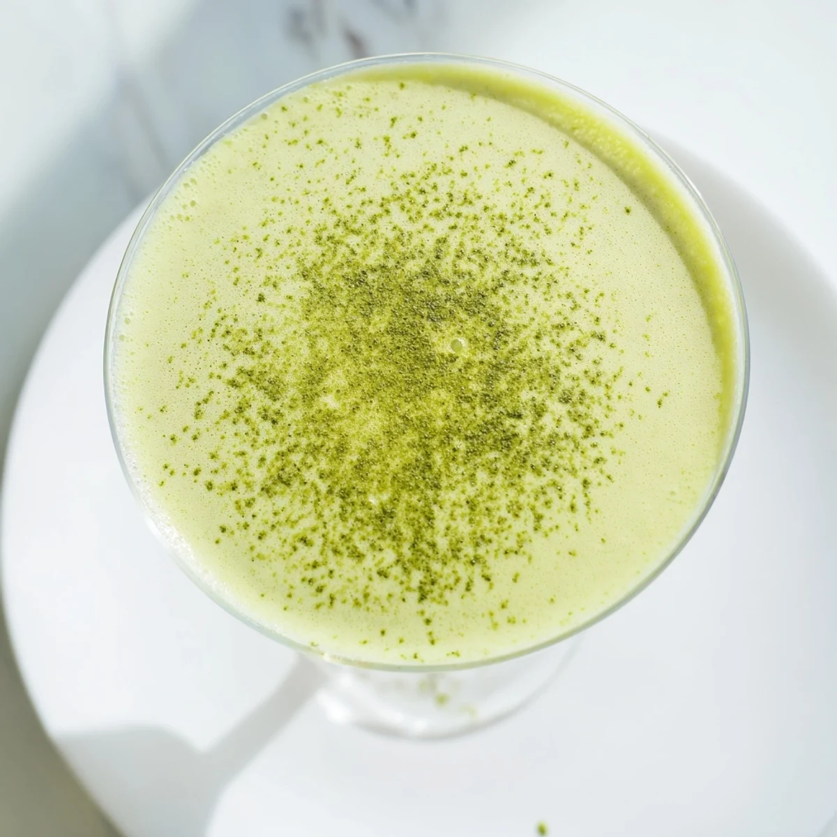 A chilled Matcha Martini cocktail with creamy vodka and matcha, garnished with white chocolate shavings and a hint of earthy green tea.  