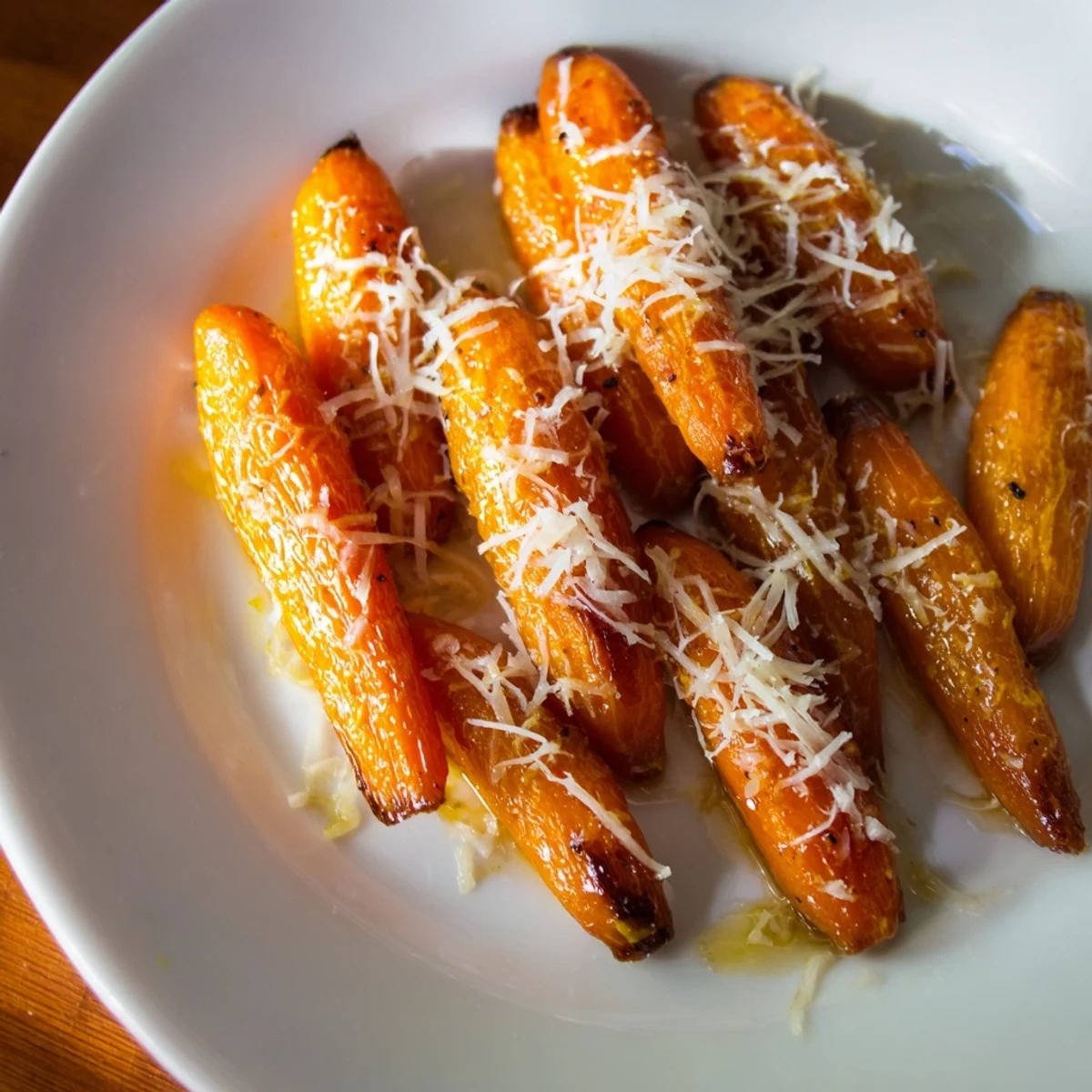 Close-up of tender baby carrots topped with melted Parmesan, perfect as a sweet-savory vegetarian snack or side dish.  