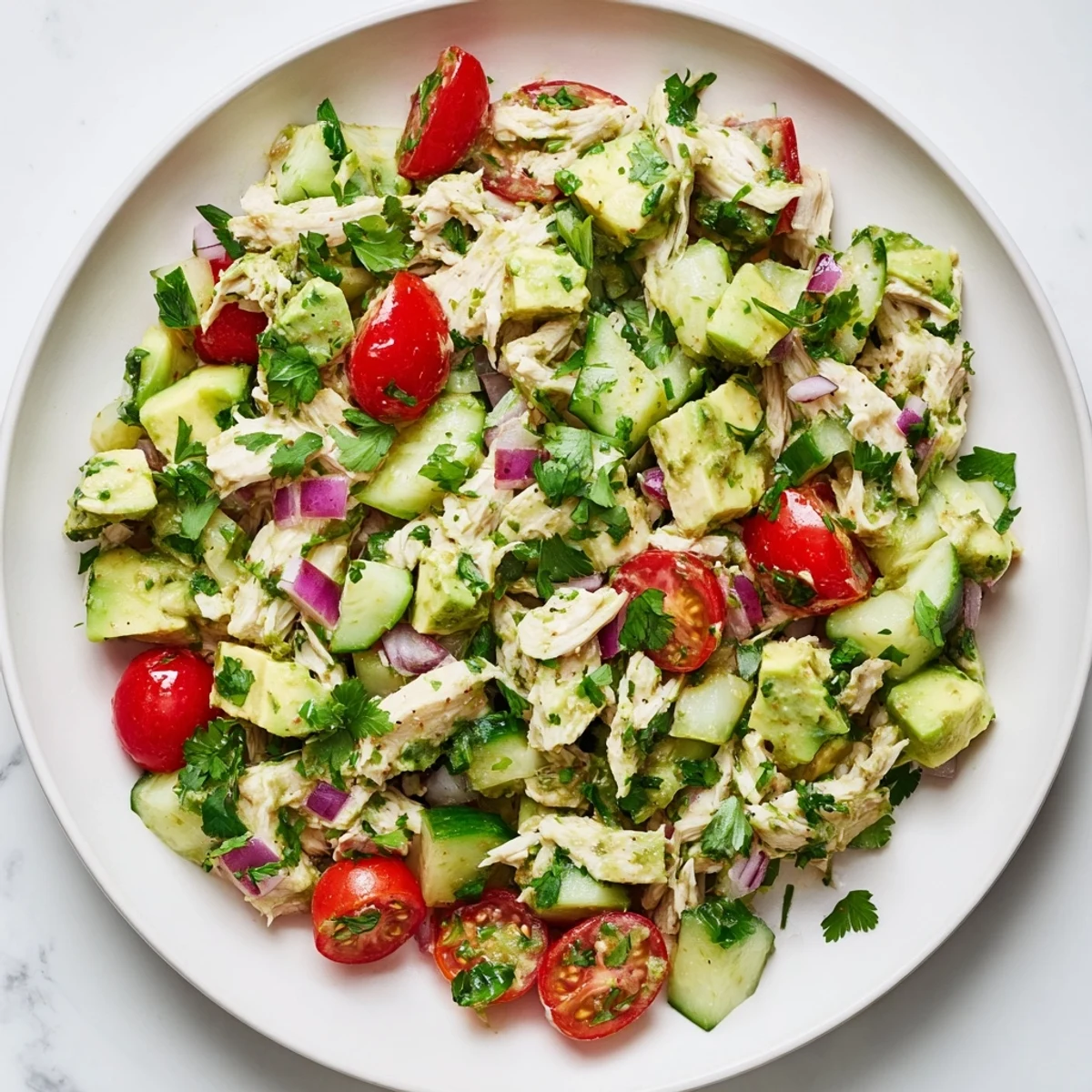 Freshly made Avocado Chicken Salad with tender diced chicken, creamy avocado chunks, and juicy cherry tomatoes served in a rustic bowl.  