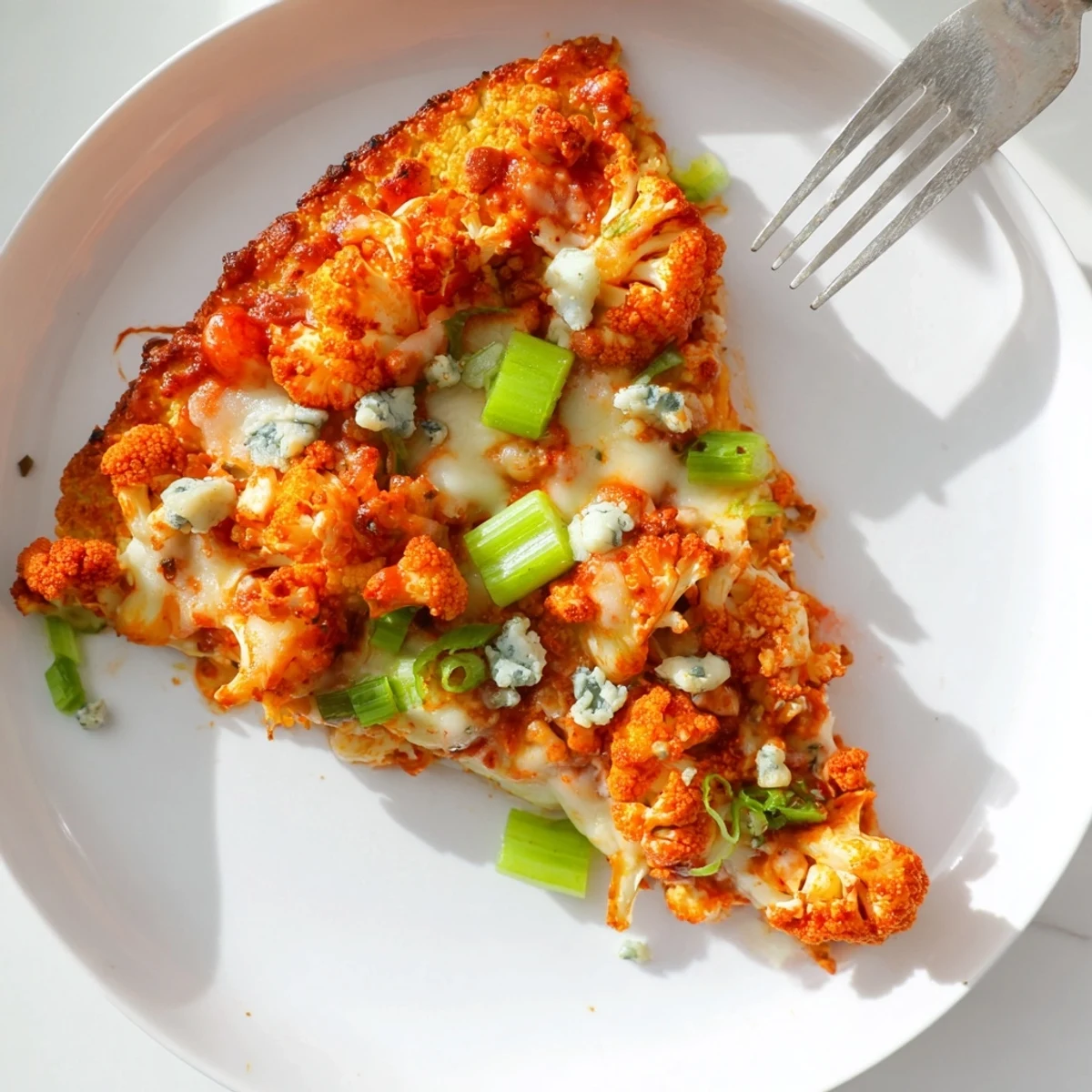 Buffalo Cauliflower Pizza sliced into wedges, revealing a crispy cauliflower crust layered with spicy buffalo sauce and melted cheese.  