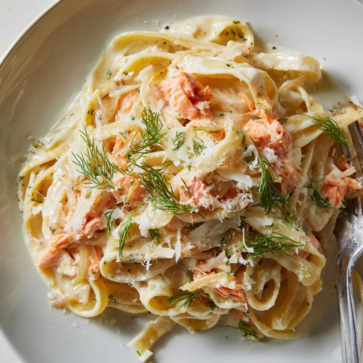 A close-up of creamy salmon pasta with flaked hot-smoked salmon, fresh dill, and lemon zest.