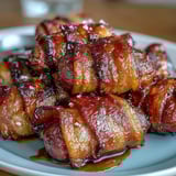 Golden, crispy bacon-wrapped smokies served warm with toothpicks at a party platter.
