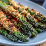 Cheesy panko-crusted Asparagus Asiago Spears arranged neatly on a platter, garnished with parsley and ready to serve.