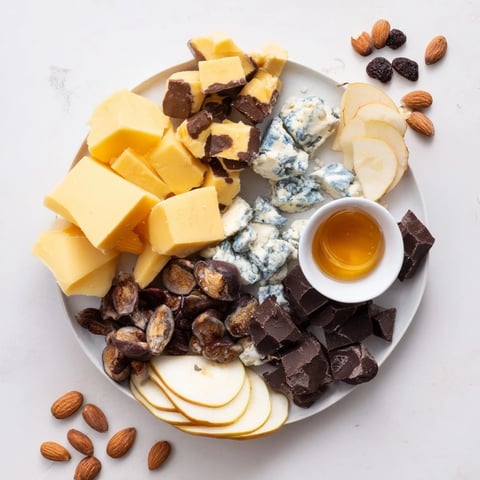 A rustic platter of Fireside Comfort & Cocoa with cheese, chocolate, and sliced fruit.