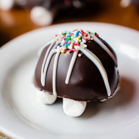 The finished Hot Chocolate Bombs show glossy chocolate spheres with a white chocolate drizzle, ready for a cozy mug.  