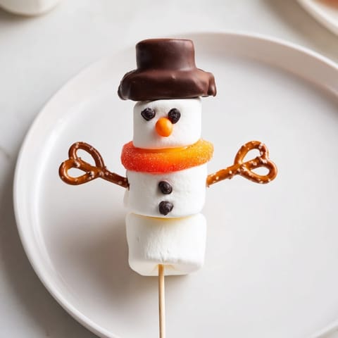Sweet marshmallow snowman sticks, decorated with chocolate, ready for kids to enjoy as a yummy snack.