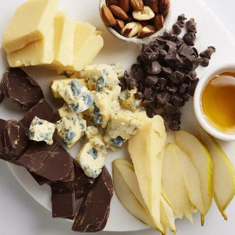 A cozy Fireside Comfort & Cocoa spread: aged cheeses, dark chocolate, and warm cocoa mugs.