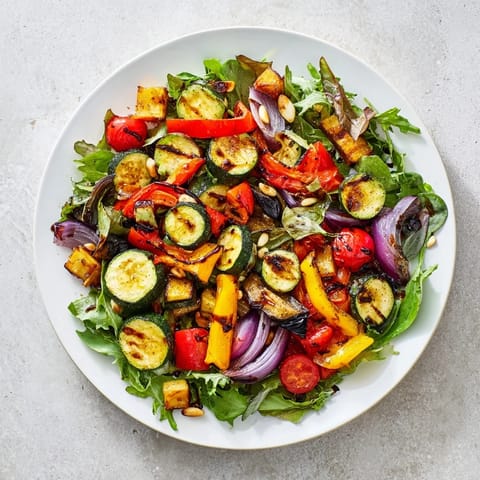 A colorful Roasted Vegetable Salad, showcasing tender roasted eggplant and bell peppers on greens.
