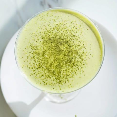 A chilled Matcha Martini cocktail with creamy vodka and matcha, garnished with white chocolate shavings and a hint of earthy green tea.  