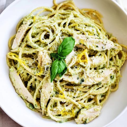 Creamy Avocado Chicken Pasta featuring al dente spaghetti tossed in a vibrant green avocado sauce, garnished with fresh basil and lemon zest.  