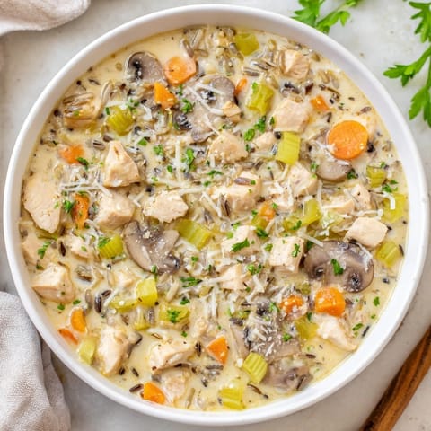 Hearty Parmesan Mushroom Chicken and Wild Rice Soup simmering in a Dutch oven with earthy mushrooms.