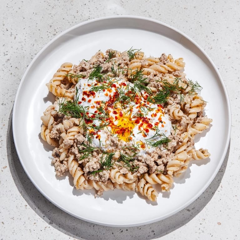 Flavorful Turkish Pasta with Ground Turkey: a delicious meal topped with fresh herbs and a buttery drizzle.