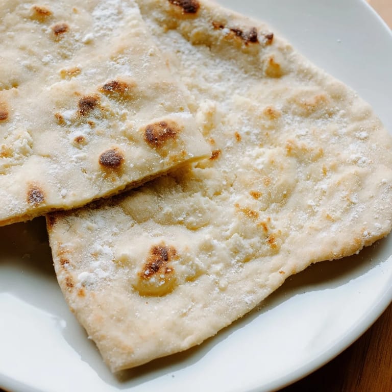 Warm cottage cheese flatbread, lightly oiled, perfect for scooping up flavorful dips.