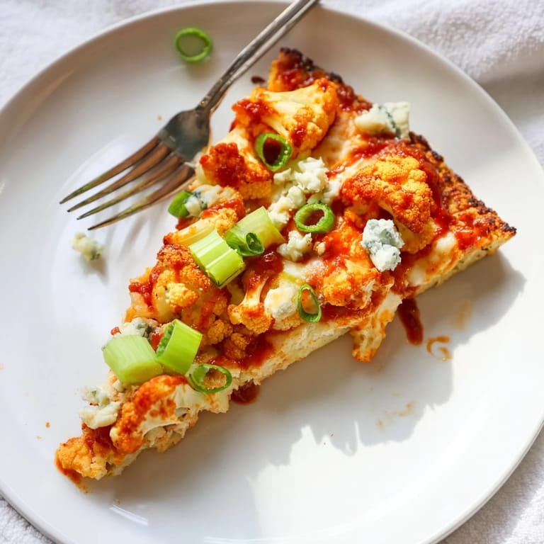 A rustic kitchen scene featuring a whole Buffalo Cauliflower Pizza topped with blue cheese crumbles and fresh parsley, ready to serve.