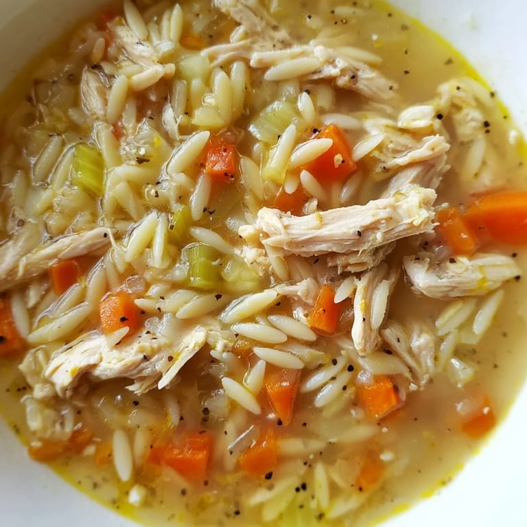 Hearty Lemon Pepper Chicken Orzo Soup in a white ceramic bowl, with vibrant carrots and celery visible in the golden, aromatic broth.