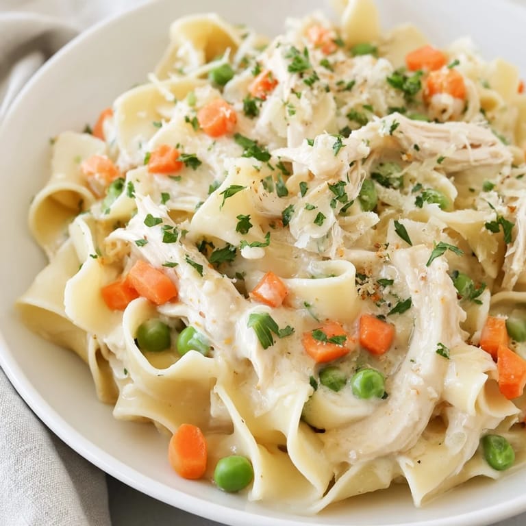 Close-up of Spring Chicken Noodle Skillet showing golden egg noodles and vegetables in a light, creamy sauce, served family-style for a comforting spring meal.