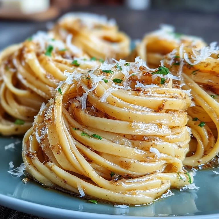 Plated truffle-infused egg pasta with silky butter sauce, Parmesan shavings, and a drizzle of truffle oil for a luxurious meal.