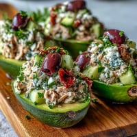Fresh Mediterranean Tuna Salad Stuffed Avocados topped with crumbled feta and parsley, ready to serve as a light lunch.