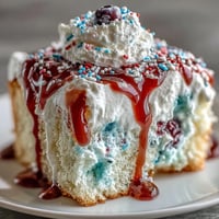 Vibrant red white blue poke cake with creamy whipped topping and festive sprinkles, perfect for Memorial Day celebrations and summer gatherings.